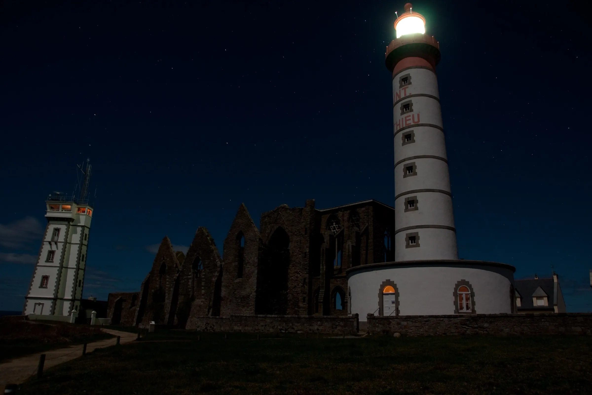 Le phare et l'abbaye en ruines veillant sur la côte, sous un ciel étoilé